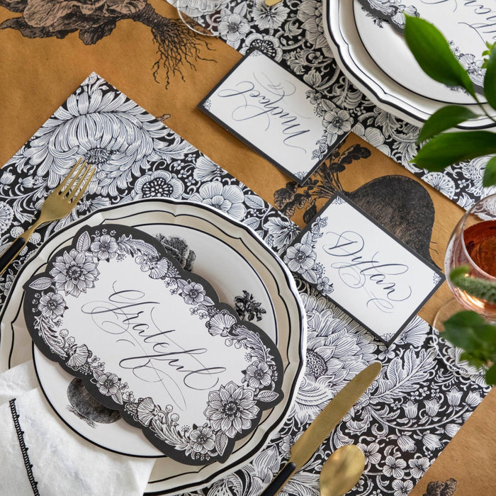 An elegant place setting featuring an Ebony Harvest Blooms Table Card with "Thankful" written on it in lovely script resting on the plate.