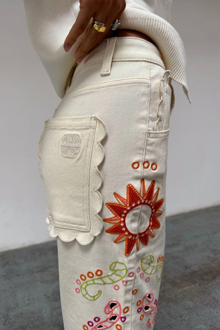 Ecru Enchanted Cut Work Scallop Jeans with a scalloped back pocket and colourful embroidered sun motif.