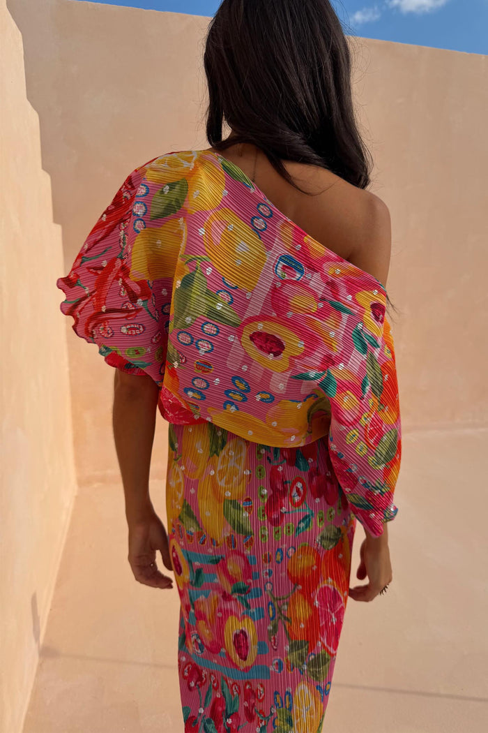 Pink pleated Fruit Tilly Dress with metallic flecks and a fruit print, featuring an off-shoulder neckline.