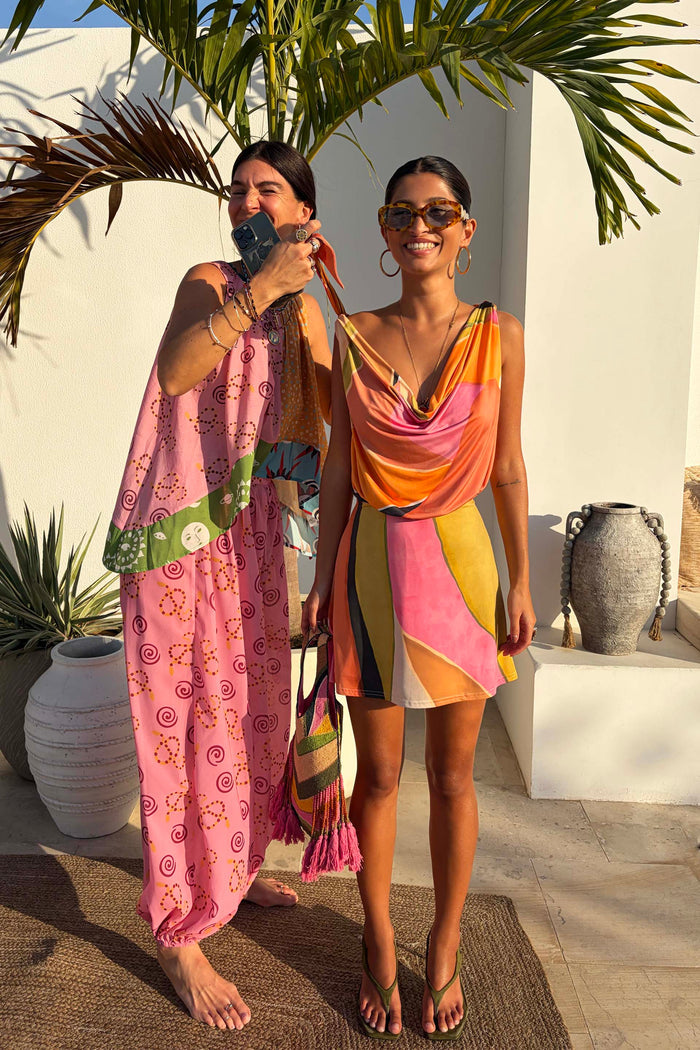 Green Abstract Leila Mini Dress with a vibrant multi-colour print and cowl neck in a sun-drenched vacation setting.