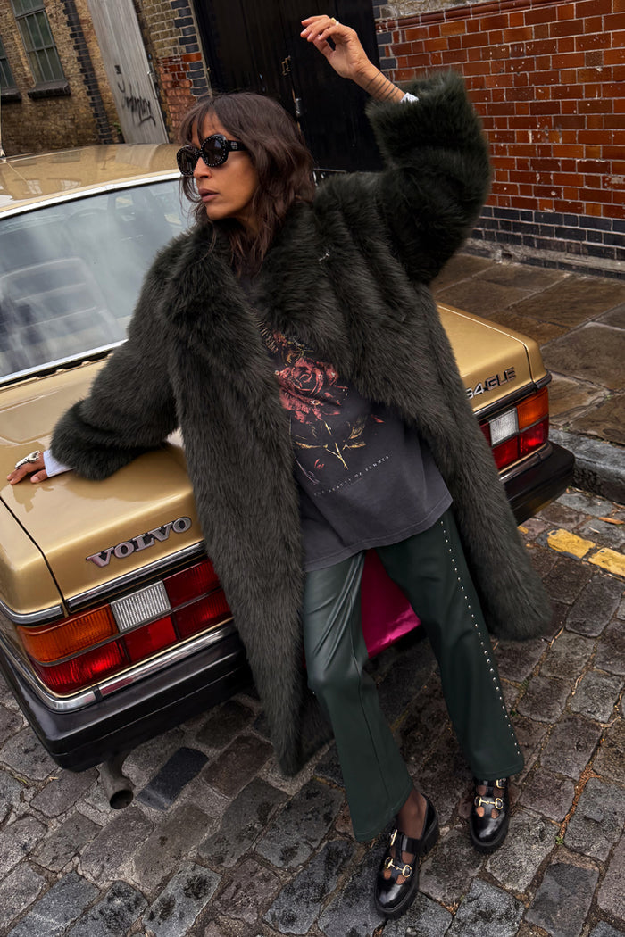 Green Faux Fur Coat in a relaxed fit, leaning against a vintage gold car on a cobblestone London street.