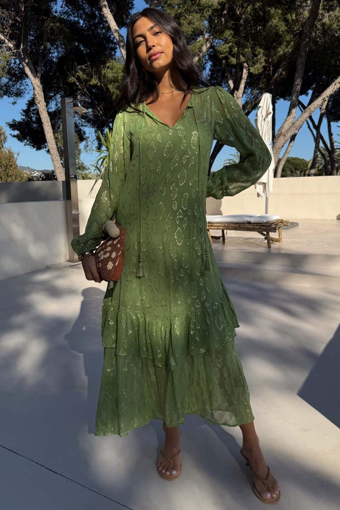 Olive Green Jacquard Harmony Dress with gold animal print, tiered ruffles and tassel neck, styled on a model outdoors.