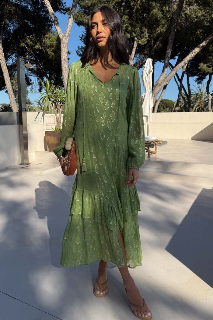 Green Jacquard Harmony Dress in olive green with gold animal print, pleated skirt and tassel neckline on a model.