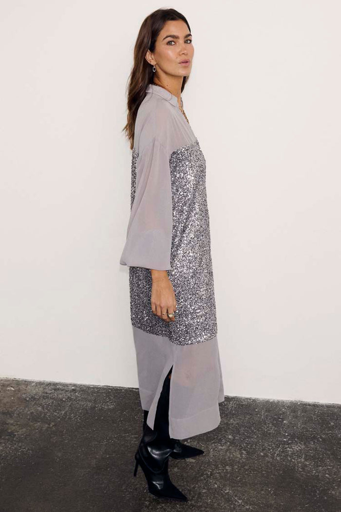 Gunmetal Sequin Lila Shirt Dress featuring silver sequins and sheer panels, styled with black pointed boots.