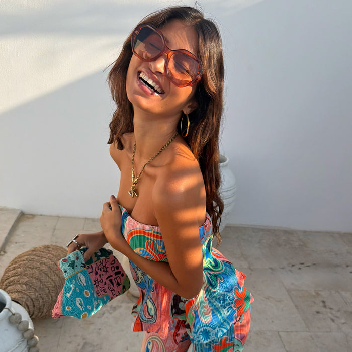 Hexagon Orange Sunglasses with light-tinted lenses, styled with a colourful patterned top for a sunny vacation look.