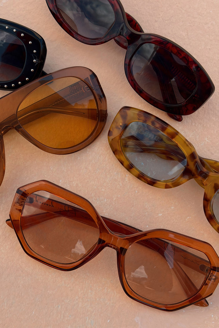 Hexagon Orange Sunglasses with light-tinted lenses, styled among various animal print and studded eyewear frames.