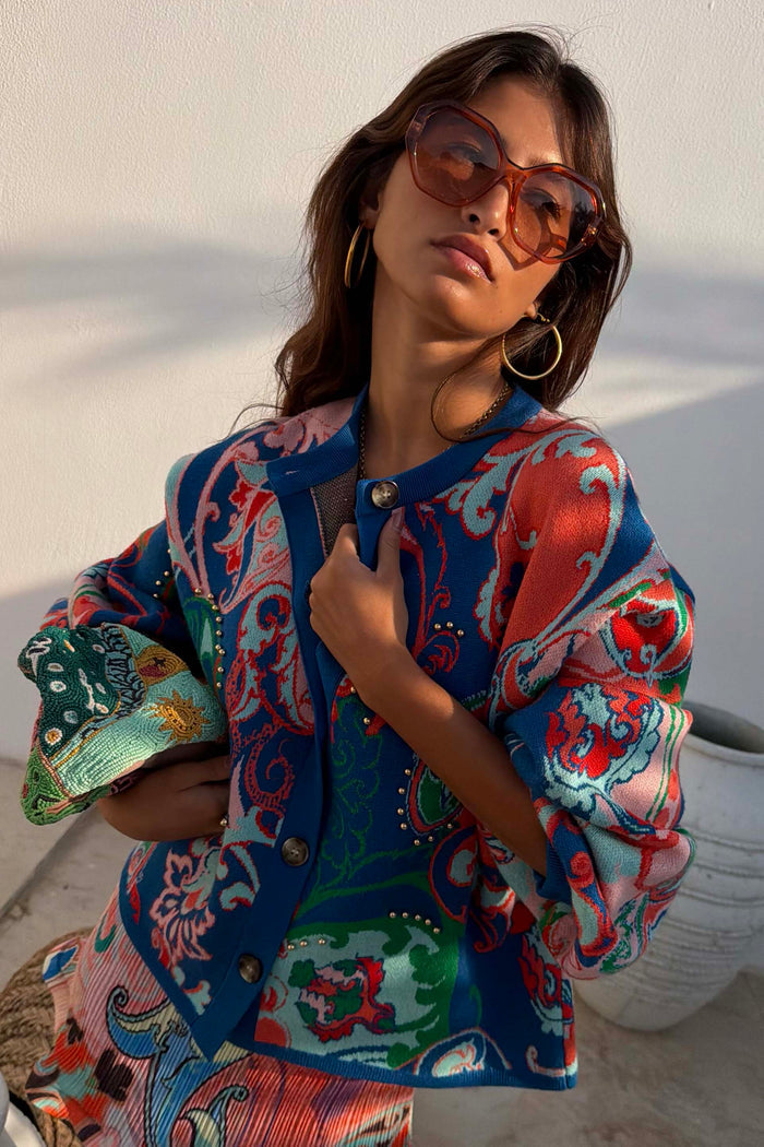 Hexagon Orange Sunglasses with light-tinted lenses, worn with a patterned knit cardigan for a vacation look.