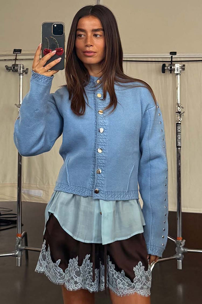 Ice Blue Studded Cardigan with silver sleeve studs and gold buttons, worn by a model in a studio mirror selfie.