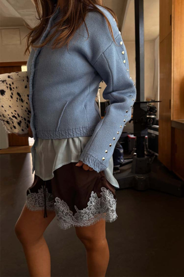 Ice Blue Studded Cardigan featuring silver metal sleeve studs and structured darts, paired with a lace-trimmed skirt.