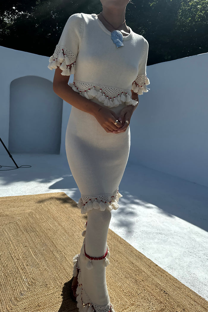 Ivory and Red Harper Dress featuring crochet tassel trim and red beading on a cream knit midaxi silhouette.