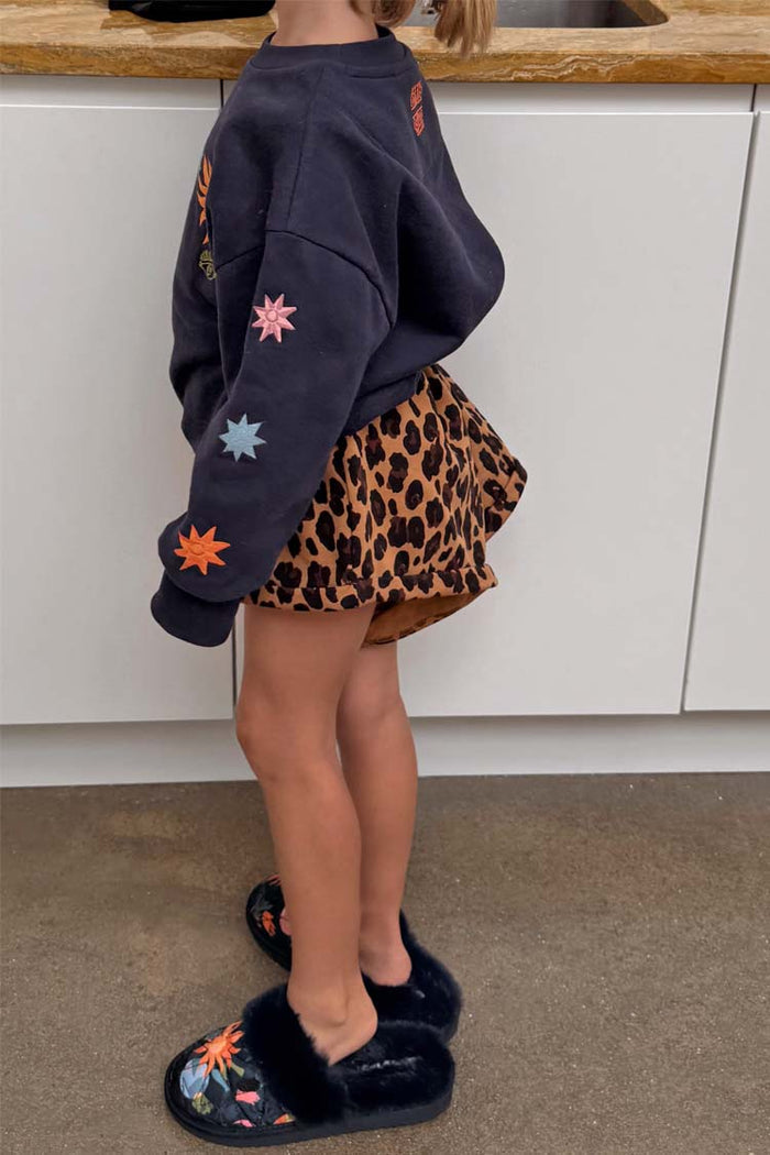 Kids Navy Charms Sweatshirt with colourful sun motifs on the sleeves, styled with leopard print shorts.