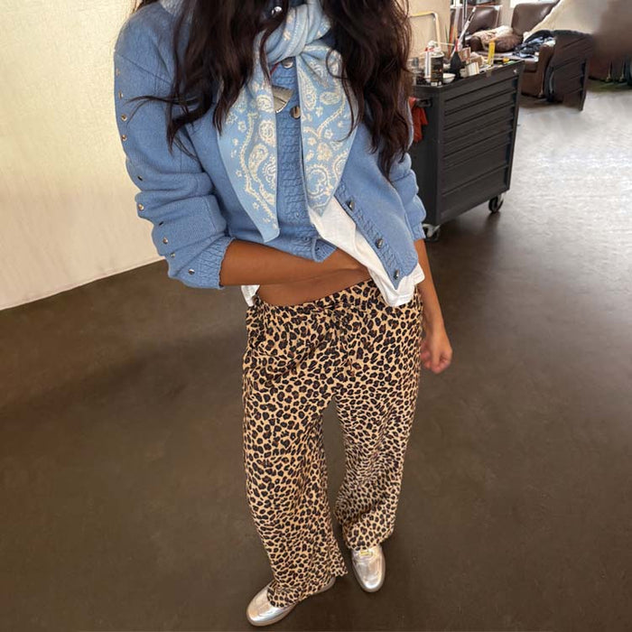 Lucia Leopard Elissa Trousers featuring a wide-leg fit and iconic animal print, styled with a blue cardigan and scarf.