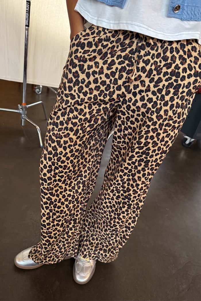 Lucia Leopard Elissa Trousers featuring a wide-leg fit and iconic leopard print, paired with silver trainers.