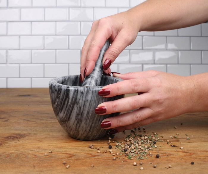Marble mortar and pestle set by RSVP International with smooth white and gray veined marble for grinding spices and herbs.