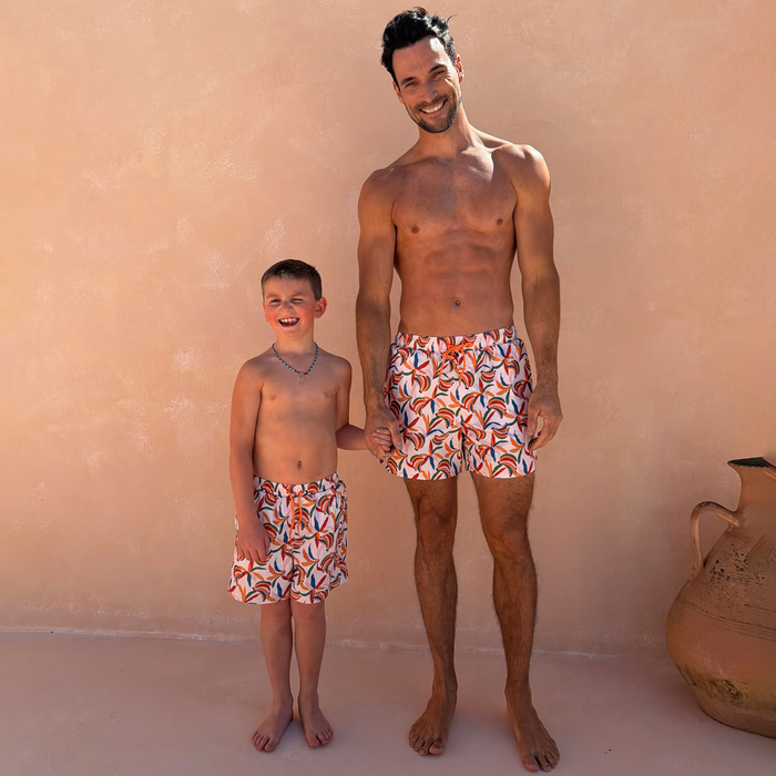 Matching men’s and boys’ Banana Swim Shorts in a cream multi-coloured recycled fabric, designed for a family vacation.