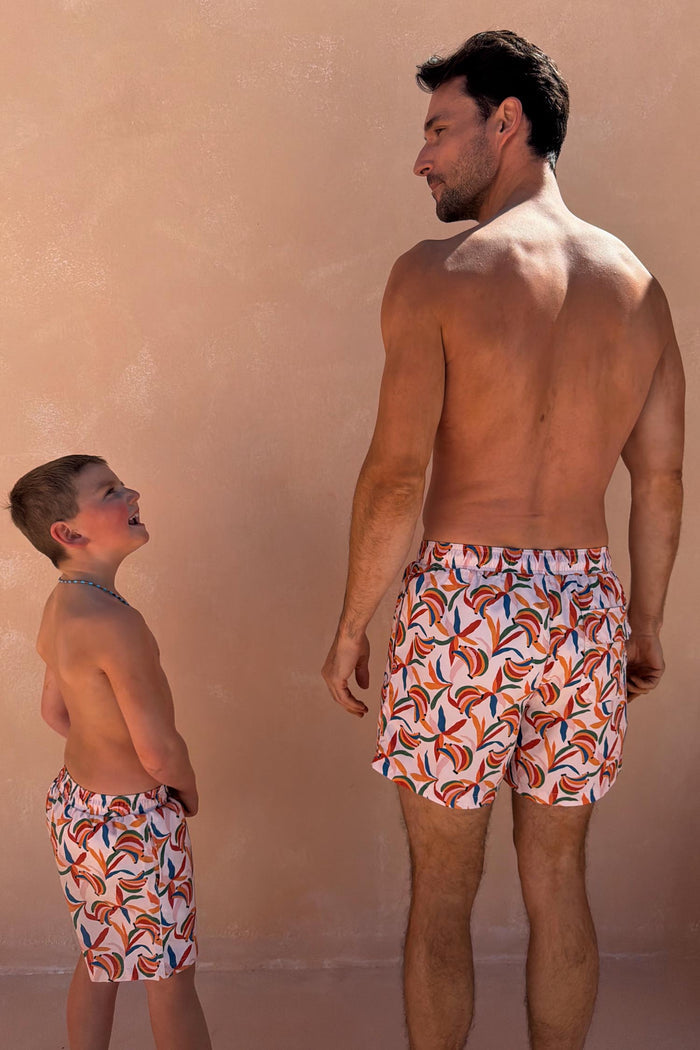 Men's Banana Swim Shorts featuring a multi-coloured print on cream, shown with matching boys' shorts for vacation.