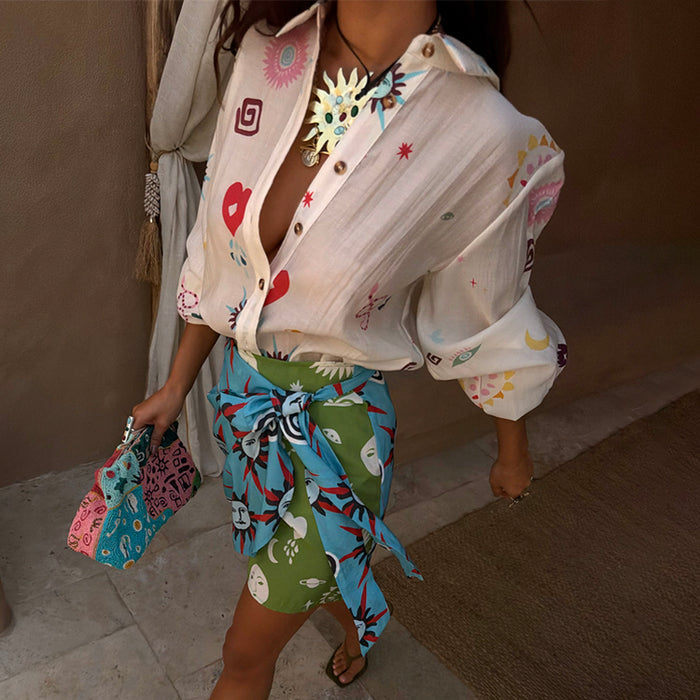 Cream Morocco Charms Marley Shirt featuring heart, sun and snake motifs, paired with a vibrant green and blue wrap skirt.