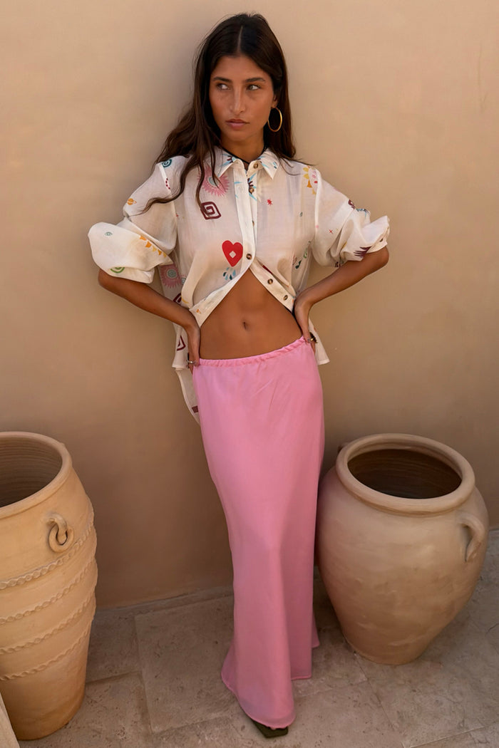 Morocco Charms Marley Shirt in cream with heart and sun motifs, worn open with a pink maxi skirt.