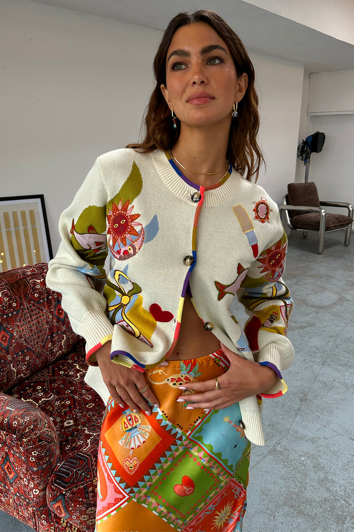 Cream Multi Enchanted Cardigan featuring colourful NFD motifs and multi-coloured trim, styled over a vibrant wrap skirt.