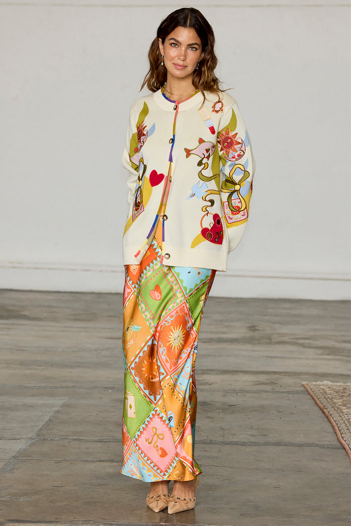 Multi Enchanted Cardigan in cream with colourful motifs and multi-coloured trim, styled over a patterned maxi skirt.