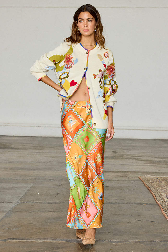 Multi Enchanted Cardigan in a cream knit with sun motifs and multi-colour trim, styled with a patterned maxi skirt.