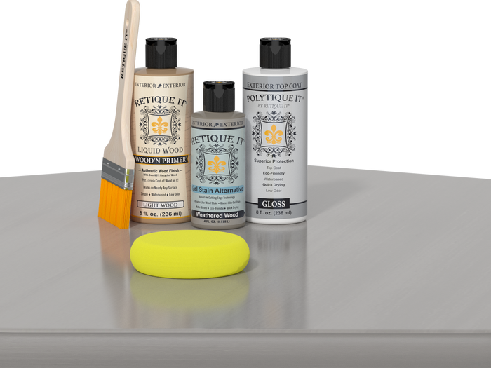 Retique It® Weathered Wood kit with brush, Wood’n Primer, Weathered Wood stain alternative, gloss top coat, and yellow sponge on a reflective surface.
