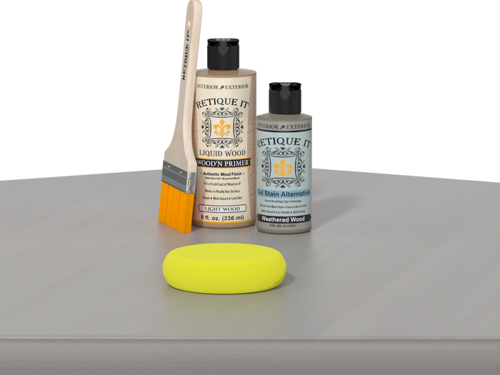 Retique It® Weathered Wood Kit with Light Wood’n Primer, Weathered Wood Gel Stain Alternative, paintbrush, and yellow sponge on a weathered wood tabletop.