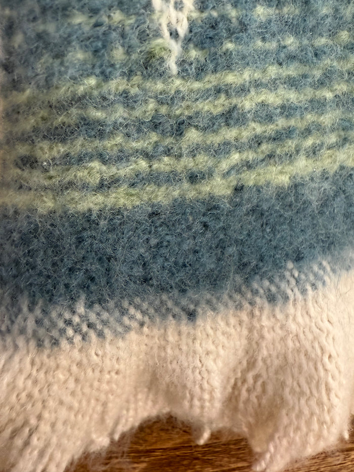 Jacquard throw blanket close-up with blue stripes and cream fuzzy texture.