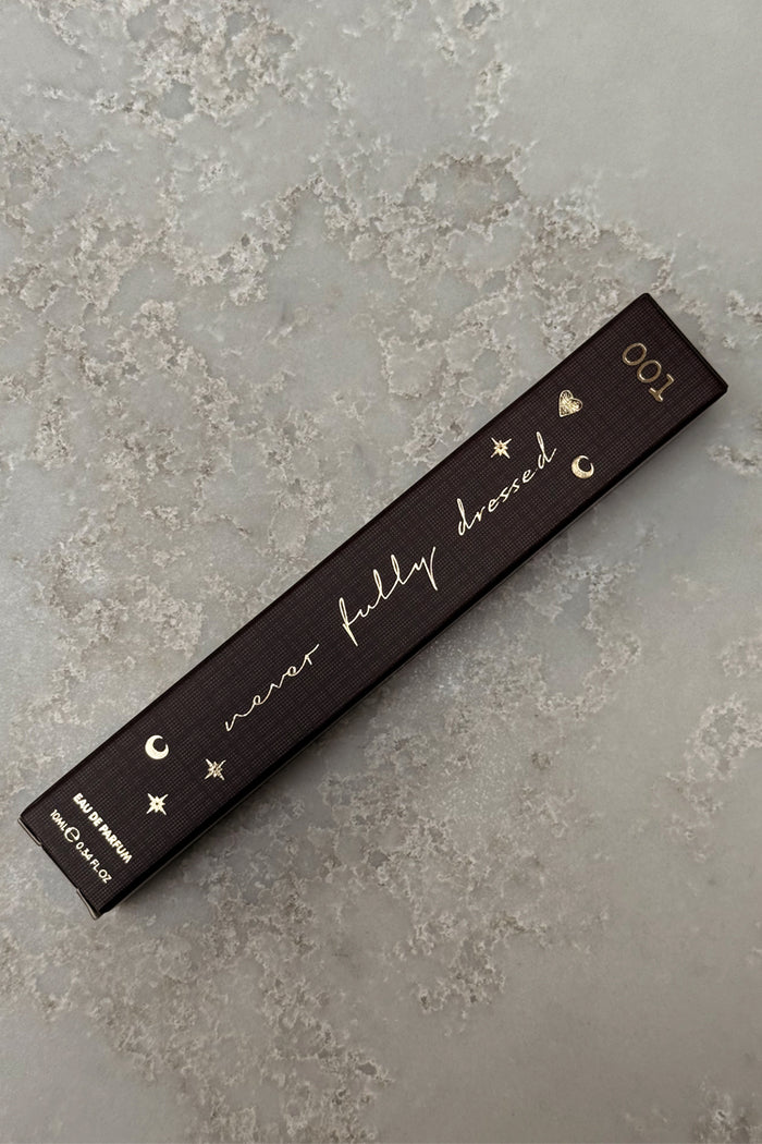 Dark brown NFD Eau De Parfum 001 10ml box with gold foil script and celestial icons on a stone surface.