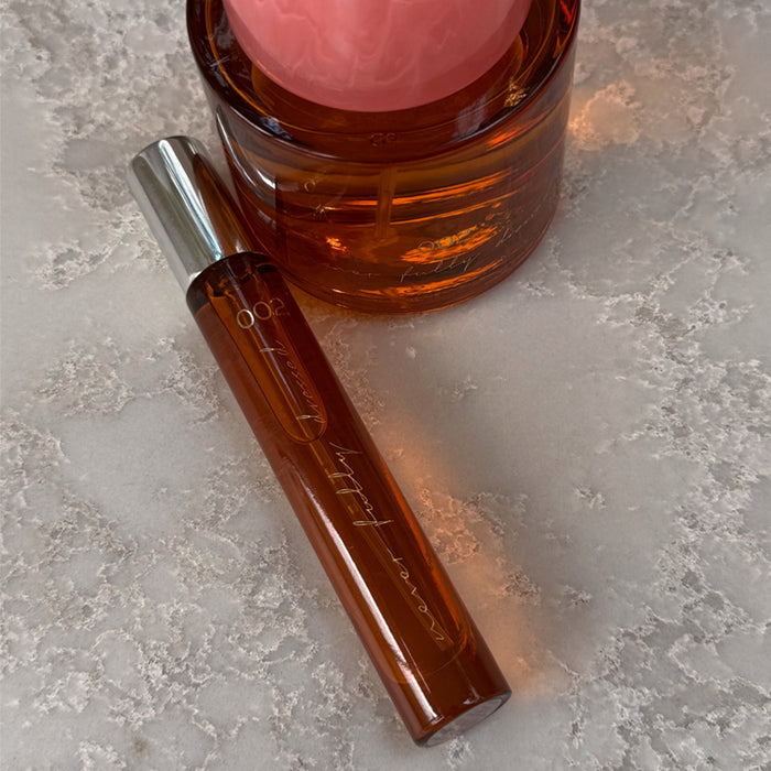 NFD Eau De Parfum 002 10ml travel spritz in amber glass with a silver cap, resting on a speckled stone surface.