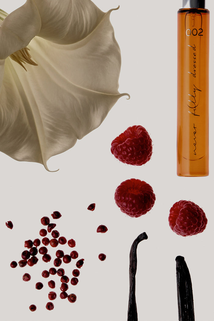 NFD Eau De Parfum 002 amber vial with fresh raspberries, pink peppercorns, vanilla pods, and a white flower.