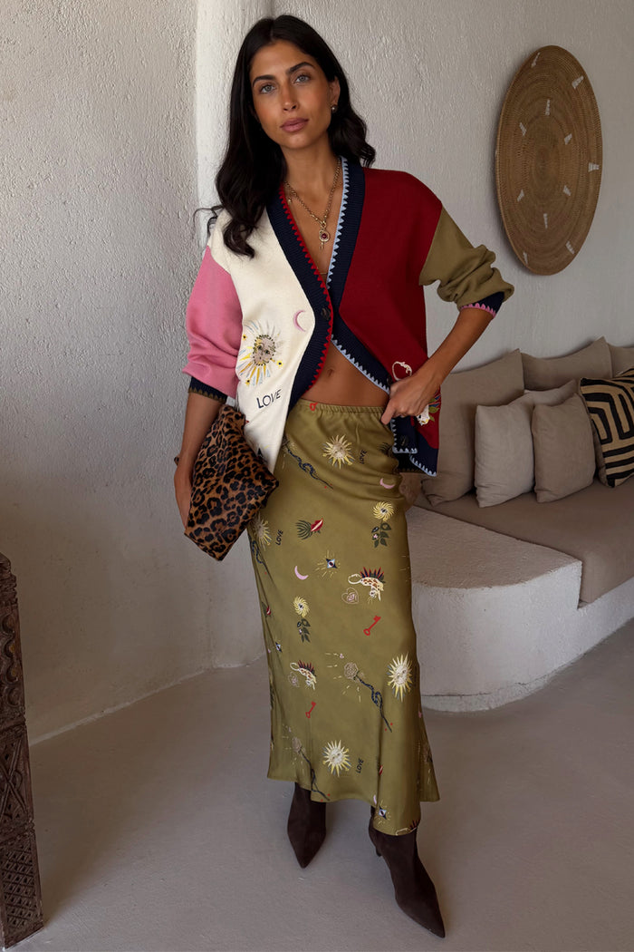 Olive Mystical Dorris Skirt featuring sun and key motifs, styled with the colour-blocked Mystical Cardigan and boots.