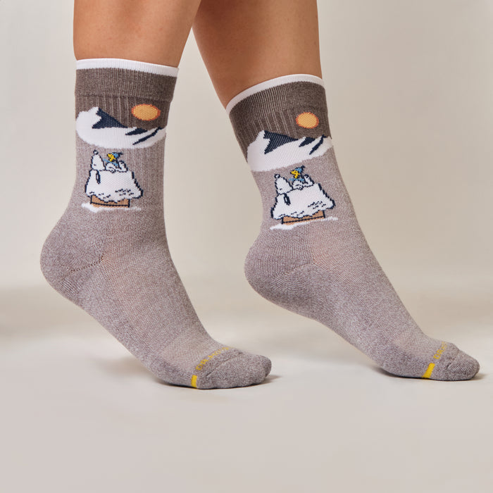 Light grey marl crew compression socks with a Peanuts mountain slope design, worn in a lifestyle setting.