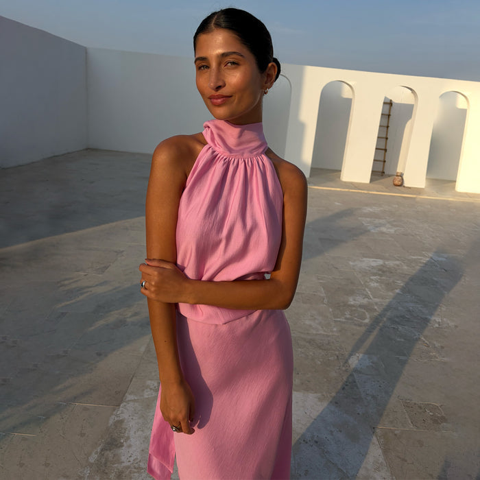Pink Billie Top with a gathered halterneck and draped fit, styled as a co-ord against a white arched backdrop.