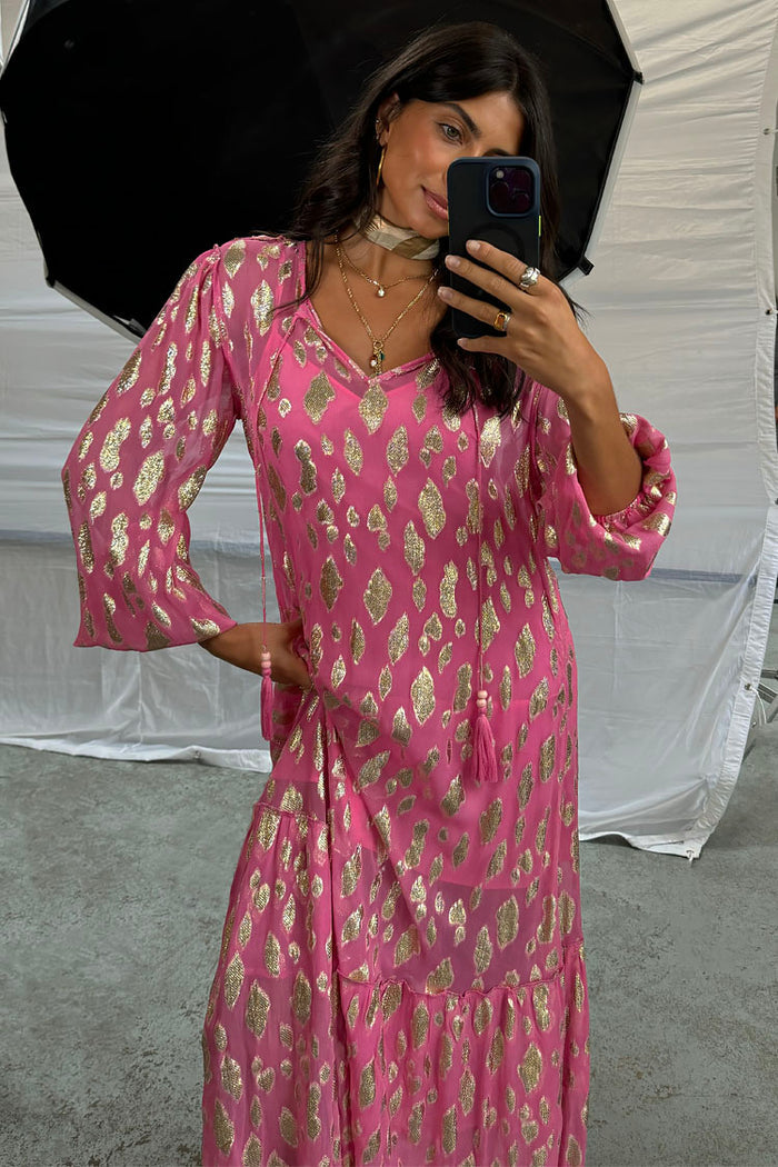 Pink Jacquard Harmony Dress featuring gold animal print, tassel neckline and long sleeves in a mirror selfie.