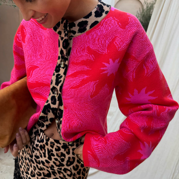Pink Soleil Cardigan featuring red sun motifs, leopard print trim, button-up front, and wide sleeves.
