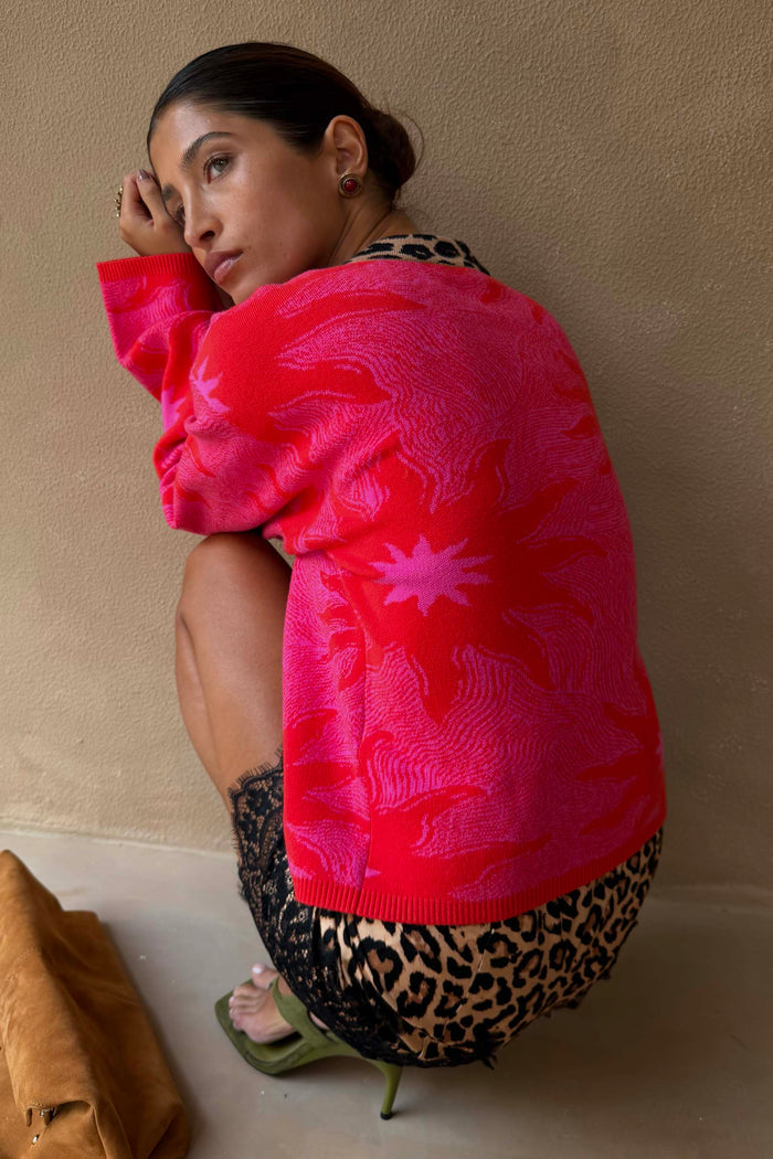 Pink boxy knit cardigan with a red Soleil print and leopard trim, designed in London and styled with a leopard skirt.