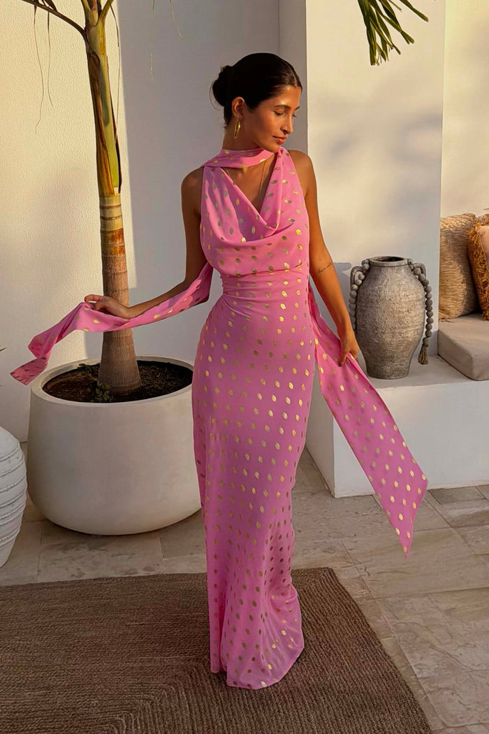 Pink Sophie Dress with gold flecks, cowl neck and multi-wear scarf, styled on a model in a sunlit terrace setting.
