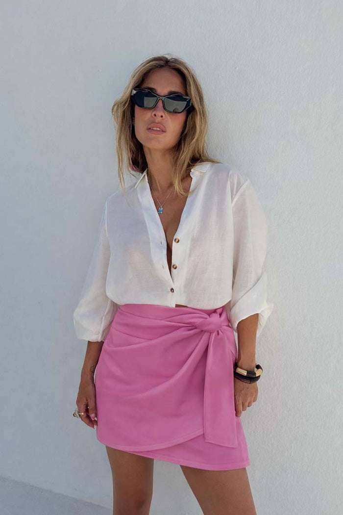 Iconic Pink Vegan Leather Mini Jaspre Skirt styled with a white shirt and dark sunglasses.