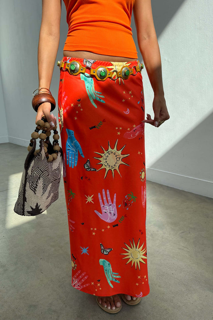 Red Celestial Dorris satin maxi skirt featuring hand-painted sun and hand motifs on a red base.