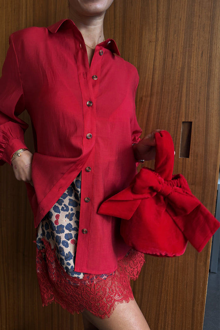 Red Velvet Bow Bag in red velvet featuring a statement bow, styled with a red shirt and leopard print skirt.