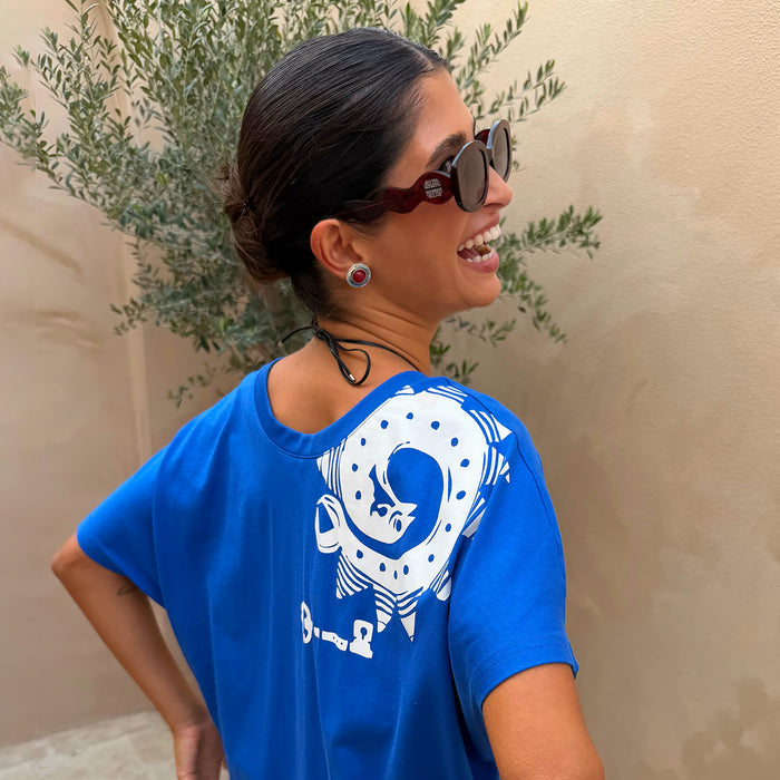 Red Wiggle Arm Acetate Sunglasses with red tortoise frames and dark lenses, styled with a bright blue graphic t-shirt.