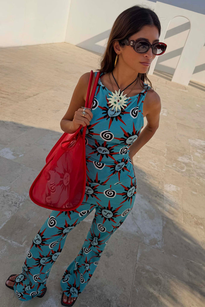 Red Wiggle Arm Acetate Sunglasses with red tortoise frames and dark lenses, styled with a blue sun-print co-ord and red bag.