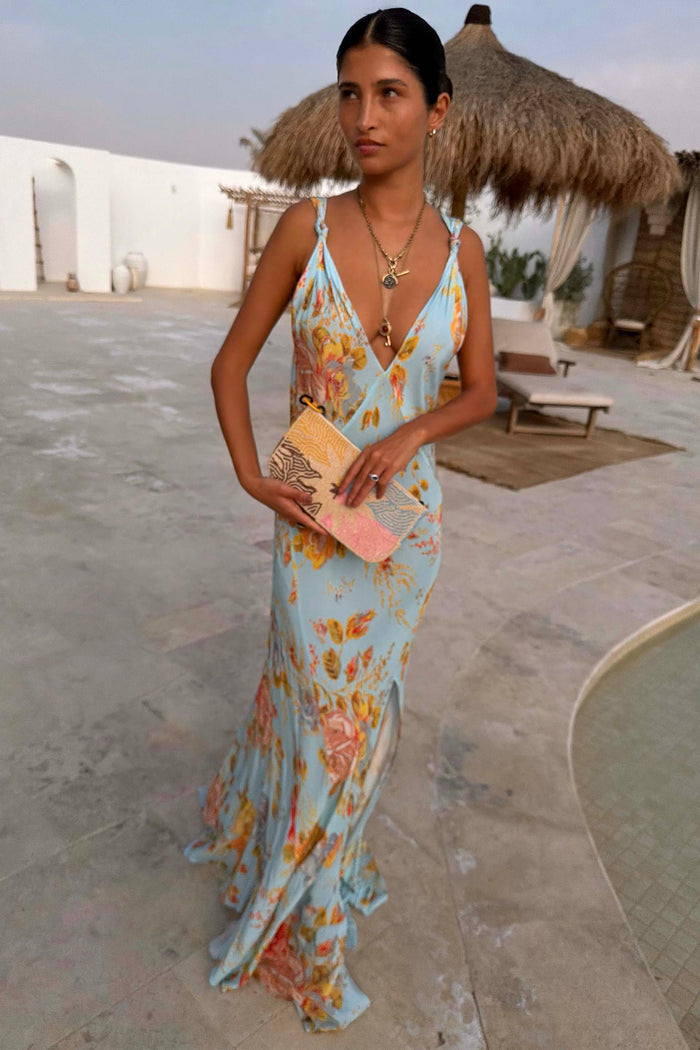 Sky Blue Floral Sofia Dress with tie-knot shoulders and a side slit, styled for a wedding guest look at a resort.