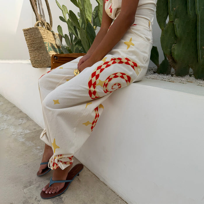White Snake Tie Side Trousers in cotton twill with red and yellow motifs, wide leg fit and adjustable tie ankles.