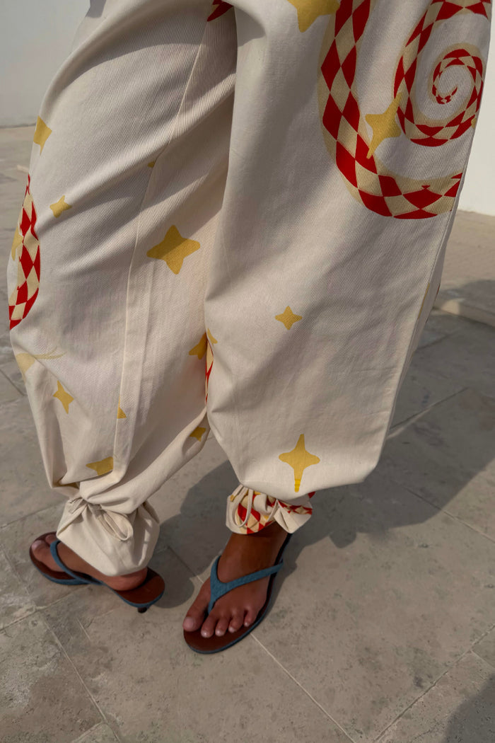 Snake Tie Side Trousers in white cotton twill with red snake and yellow star motifs and multi-wear ankle ties.