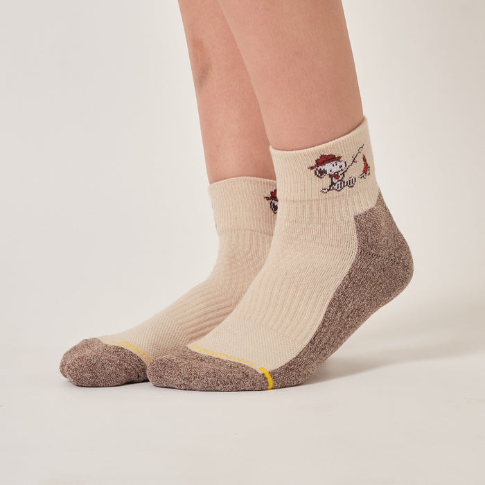 Ivory oat quarter compression socks with a Snoopy campfire design, worn in an outdoor setting.