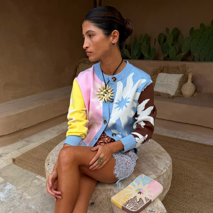 Soleil Hollie Cardigan with pastel sun motifs and soft-touch knit, styled on a model in a Mediterranean-style courtyard.
