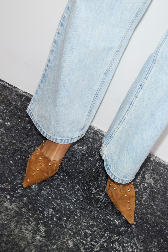 Tan Suede Scallop City Mules with gold studs and scallop edge, paired with light blue wide-leg jeans.