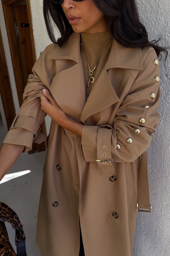 Tan Trench Coat with gold studs along the sleeve and buckled cuffs, a versatile statement staple.